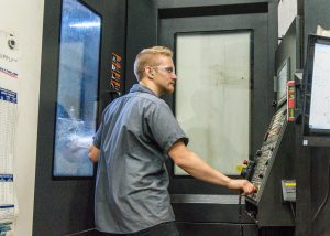 An ExacTech employee checking progress in a CNC machine shop