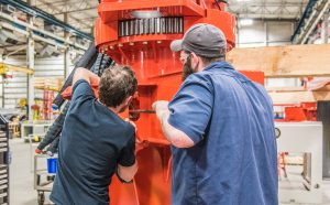 Two Marine Travelift assemblers working on an orange Shuttlelift Mobile Gantry Crane